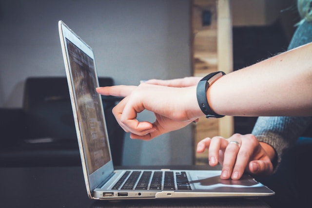 two people at laptop with one pointing to the screen