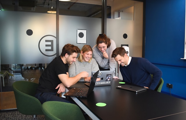 Four people gathered around an open laptop