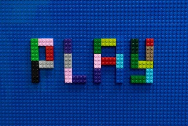 the word 'play' spelled out in Lego bricks on a blue base sheet